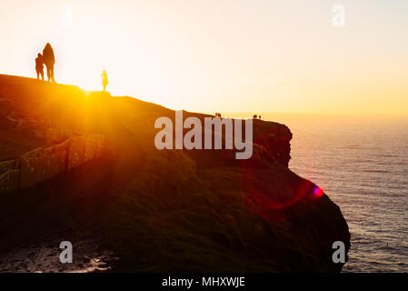 Persone a clifftop guardando il tramonto, Liscannor, Clare, Irlanda Foto Stock