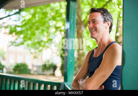 Uomo maturo in piedi sotto il palco per spettacoli, sorridente Foto Stock