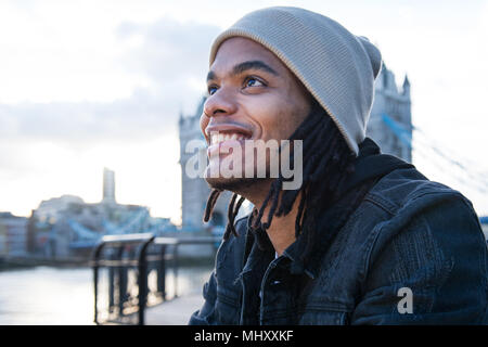 Ritratto di giovane uomo seduto all'aperto, sorridente, London, England, Regno Unito Foto Stock
