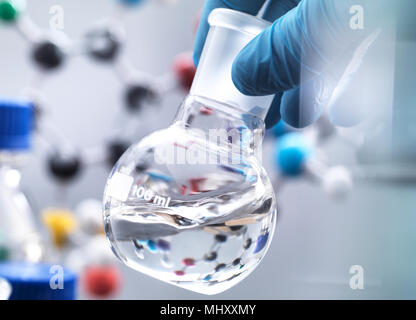 Scienziato preparazione di formula chimica in un pallone da laboratorio durante un esperimento, modello molecolare in background Foto Stock