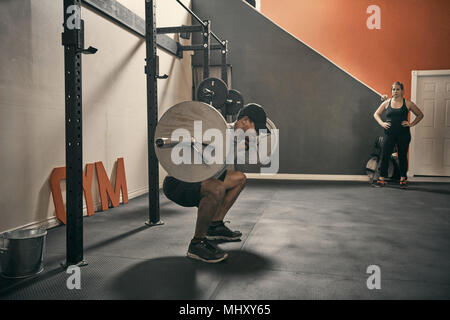 Uomo in palestra pesi utilizzando barbell Foto Stock