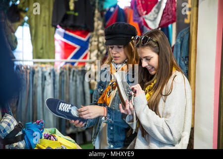 Amici navigando abbigliamento vintage parsimonia nel negozio Foto Stock