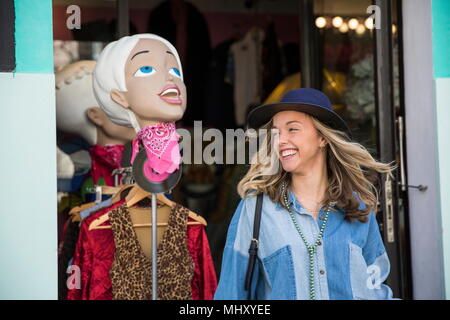 Giovane donna lasciando negozio di abbigliamento sorridente Foto Stock