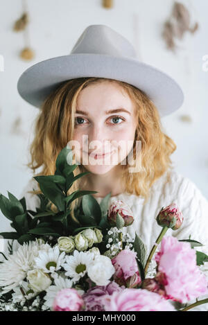 Ritratto di donna holding mazzo di fiori, guardando alla fotocamera a sorridere Foto Stock