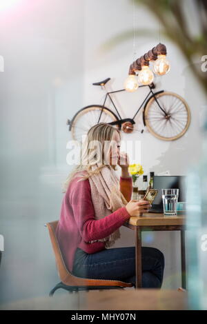 Donna seduta al cafe, guardando a smartphone Foto Stock