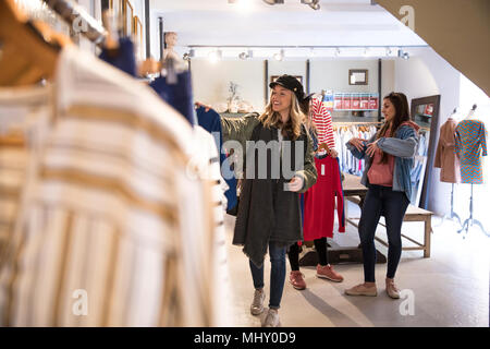 Tre amici, shopping, guardando i vestiti su rotaia in negozio Foto Stock