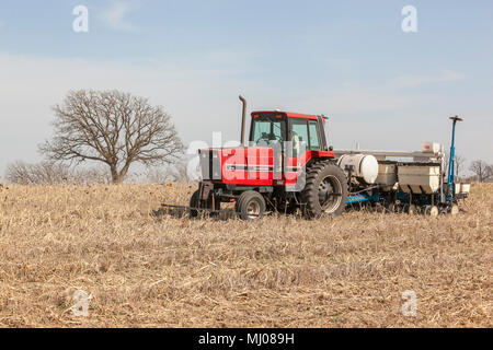 Un trattore Case IH una trazione Kinzie piantatrice di mais attraverso un raccolto di coperta. Foto Stock