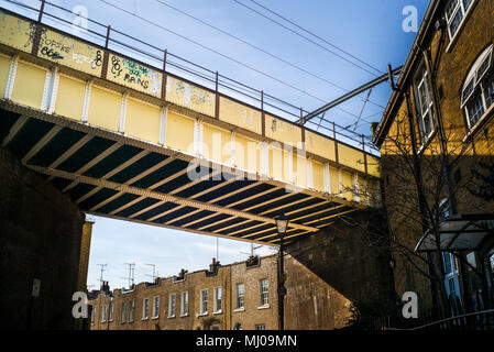 Ponte ferroviario vittoriano in ferro che si estende tra gli edifici della città di Camden sotto il sole Foto Stock