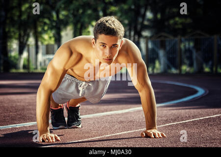 Attraente forte uomo fitness facendo esercizi in posizione di parcheggio Foto Stock