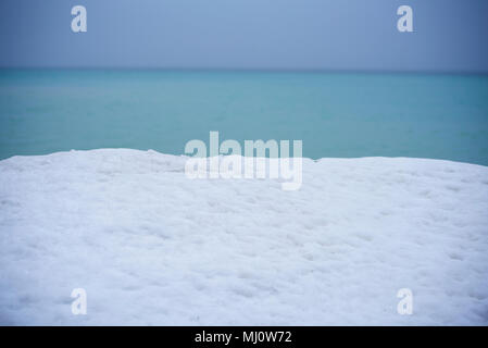 Il tardo inverno di haze e di cielo nuvoloso produce silenziato blu e azzurro acqua e cielo toni sul Lago Ontario, Canada. Foto Stock