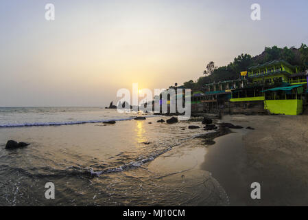 Cafe tropicale sulla spiaggia rocciosa al tramonto Foto Stock