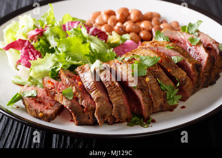 Messicana preparata di fresco affettato bistecca di manzo con lattuga e fagioli close-up su una piastra orizzontale. Foto Stock