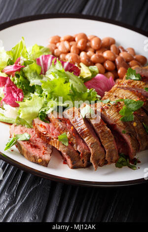 Grigliate di carne Asada bistecca con insalata di fagioli e close-up su una piastra verticale. Foto Stock