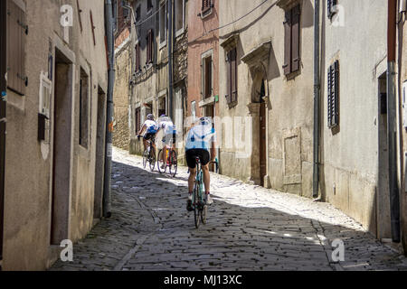 Istria centrale, Croazia - 19 Aprile 2018: I ciclisti a cavalcare giù lungo la stretta strada di ciottoli nell'antica città di Motovun Foto Stock