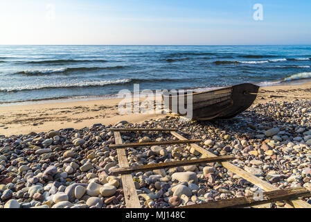 Boda costa est della riserva naturale su Oland, Svezia. Piccole casette di legno canotto in nero legato con una corda sulla spiaggia di sabbia e costa rocciosa su un soleggiato mattino di primavera Foto Stock