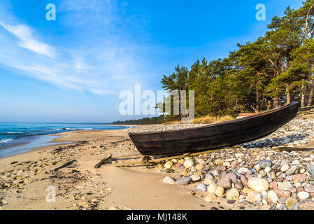 Boda costa est della riserva naturale su Oland, Svezia. Piccole casette di legno canotto in nero legato con una corda sulla spiaggia di sabbia e costa rocciosa su un soleggiato mattino di primavera Foto Stock