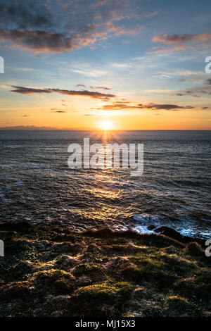 Una foto degli ultimi raggi di sole risplendere la caduta sulla cima di una scogliera sul mare a Malin Head, Irlanda Foto Stock