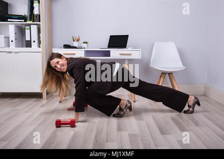 Foto di imprenditrice facendo Pushups su pavimento in legno duro Foto Stock