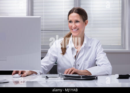 Ritratto di una donna felice medico con stetoscopio sulla scrivania Foto Stock