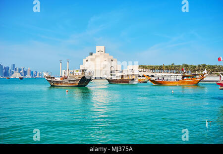 Numerose in legno barche Dhow in brillanti acque blu del Golfo Persico, con una vista su edifici moderni di Doha, in Qatar. Foto Stock