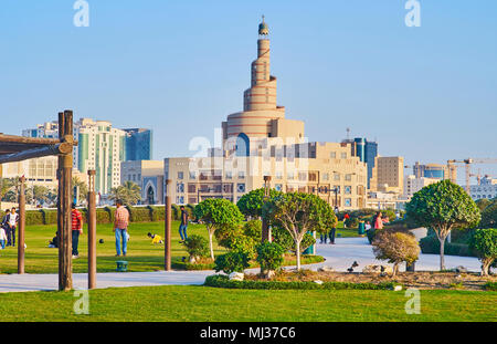 DOHA, Qatar - 13 febbraio 2018: la gente a piedi e giocare nel Souq Waqif park con minareto a spirale di Al Fanar moschea di sfondo, il 13 febbraio in Foto Stock