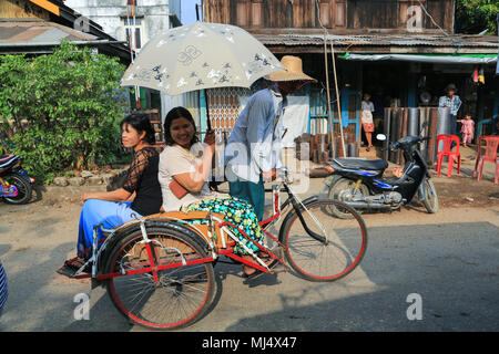 Un tri-shaw conducente di trasportare i suoi passeggeri e la loro shopping a Maubin, una città sul fiume Myitmaka, nel delta di Irrawaddy, Myanmar (Birmania). Foto Stock