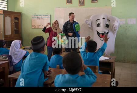 BENGKULU, Indonesia (Aprile 06, 2018) Lt. George Walrath, dalla Hacienda Heights, in California, e partenariato Pacifico 2018 (PP18) salute dentale mascotte "Toothy" dimostrare la salute dentale delle pratiche per gli studenti di SDN 77 Scuola Elementare di Bengkulu, Indonesia. PP18's missione è lavorare collettivamente con host e nazioni partner per migliorare l'interoperabilità a livello regionale di emergenza e capacità di risposta, aumentando la stabilità e la sicurezza nella regione e favorire la nascita di nuove e durature amicizie in tutta la regione Indo-Pacifico. Pacific Partnership, ora nel suo tredicesimo iterazione, è la più grande multinazionale annuale Foto Stock