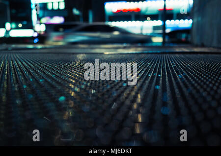 Abstract night city, sfondo scuro su strada bagnata con vetture sfocata. Messa a fuoco selettiva Foto Stock