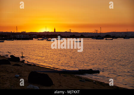 La vista della città di Lisbona con il 25 di aprile Bridge (Ponte 25 de Abril) e Cristo Rei sul fiume Tago dalla banca di Seixal nella luce del tramonto. L Foto Stock