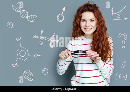 Scienziato emotivo in possesso di una lente di ingrandimento e sorridente Foto Stock