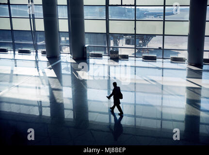 Elevato angolo di visione dell uomo che cammina lungo la parete in vetro in airport terminal . Foto Stock