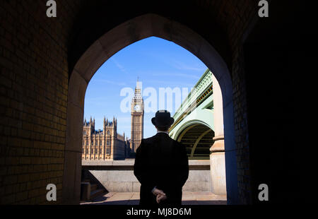 Vista posteriore di uomo che indossa mantello nero e cappello bowler in piedi vicino a Westminster Bridge dal fiume Tamigi, il Big Ben e le Camere del parlamento del dista Foto Stock