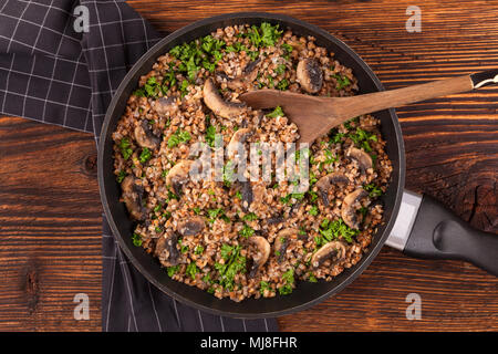 Il grano saraceno risotto con funghi secchi in padella dal di sopra su un tavolo di legno. Mangiare vegetariano concetto. Foto Stock