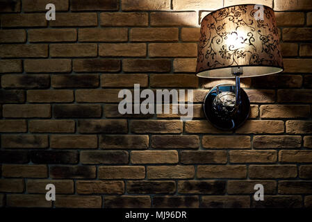 Una lampada incandescente al buio su un muro di mattoni. Uno sfondo, un  muro di mattoni texture con una lampada. Spazio di copia Foto stock - Alamy
