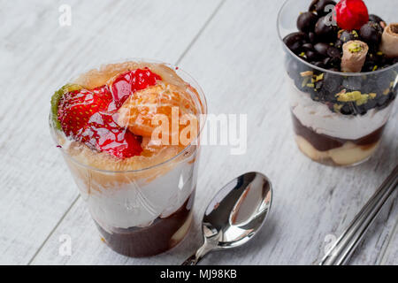 Frutta e scaglie di cioccolato Semifreddo con yogurt in coppa di vetro bianco su una superficie di legno Foto Stock