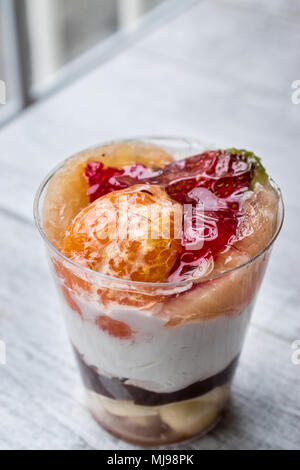 Mandarino e Parfait di fragole con yogurt in coppa di vetro bianco su una superficie di legno Foto Stock