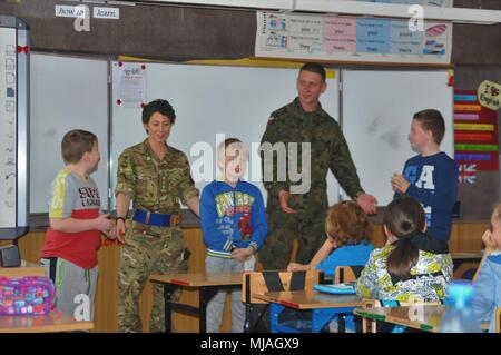 Regno Unito esercito Capt. Alice Williams, responsabile di ricognizione, assegnato per primo la regina Dragoon Guards e polacco Sgt. Ślósarek, team leader, assegnato alla XV Brigata meccanizzata, dare una presentazione delle tradizioni per studenti polacchi presso la scuola primaria sono in numero di quattro nella Giżycko, Polonia il 25 aprile 2018. Questi soldati sono parte dell'esclusiva, multinazionale gruppo di combattimento composta di Stati Uniti, Regno Unito, croato e soldati rumeni che servono con il polacco della XV Brigata meccanizzata come una forza di dissuasione nel nord-est della Polonia a sostegno della NATO in avanti rafforzata presenza. (U.S. Foto dell'esercito da Capt. Gar Foto Stock