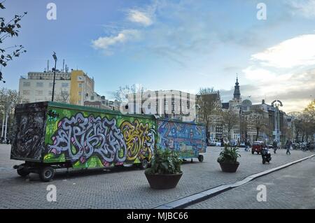 Amsterdam, Paesi Bassi: due carrelli di cibo dipinto con graffiti street art il parcheggio sulla piazza Nieuwmarkt in centrum, tra i pedoni Foto Stock