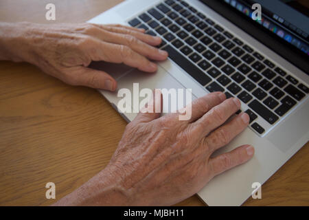 Close up di pensionati mani usando un computer portatile Foto Stock