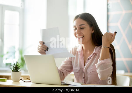 Felice giovane donna eccitato dalla lettura buona notizia nella Lettera Foto Stock