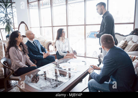 Giovane team di collaboratori di grande discussione aziendale nel moderno ufficio coworking. Il lavoro di squadra di persone concetto. Foto Stock