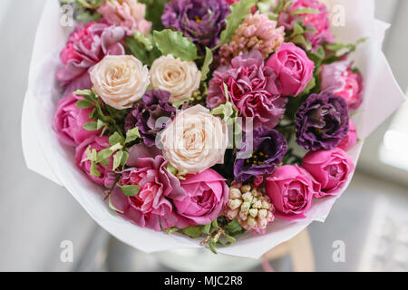 Molla di variopinti colori. Il lavoro del fioraio presso un negozio di fiori. Viola e rosa bouquet di fiori su un tavolo di legno. Foto Stock