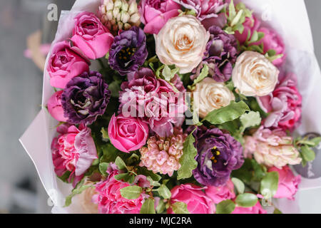 Molla di variopinti colori. Il lavoro del fioraio presso un negozio di fiori. Viola e rosa bouquet di fiori su un tavolo di legno. Foto Stock