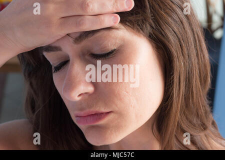 Close up ritratto di soggetti di razza caucasica giovane donna con gli occhi chiusi e la mano sulla fronte come avente un mal di testa. Foto Stock