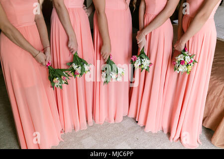 Bella bridesmaids con mazzi di fiori in casa. Modello di bellezza delle ragazze in un colorato abiti da sposa. cinque persone Foto Stock