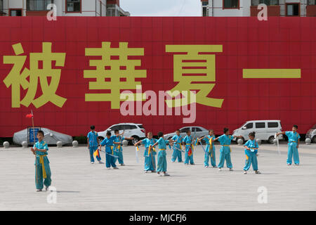 Giovani cinesi formazione, bambino, ragazzo che esercitano con la spada per arti marziali tradizionali in Tianshui city square, Cina e Asia Foto Stock