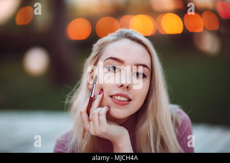 Giovane donna graziosa pittore sorriso e tracciare nel parco. Close up ritratto con spazzole. Foto Stock