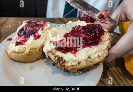 Vista ravvicinata di scones rabboccato con clotted cream e confettura di lamponi. Foto Stock