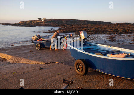 I pescatori tirare le piccole chiatte sulla rampa in calcestruzzo Foto Stock