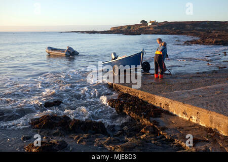 I pescatori tirare le piccole chiatte sulla rampa in calcestruzzo Foto Stock